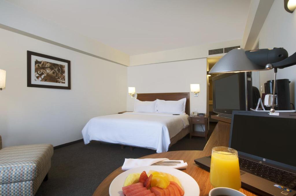 a hotel room with a bed and a table with a plate of fruit at Fiesta Inn Puebla Finsa in Puebla