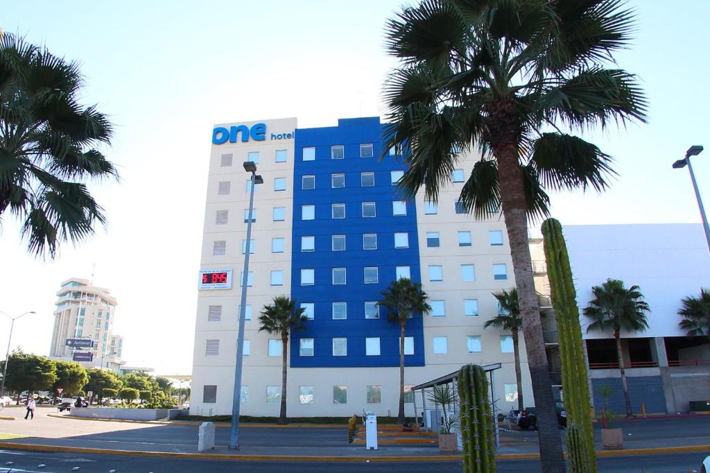 un edificio azul y blanco con palmeras delante en One Culiacan Forum en Culiacán