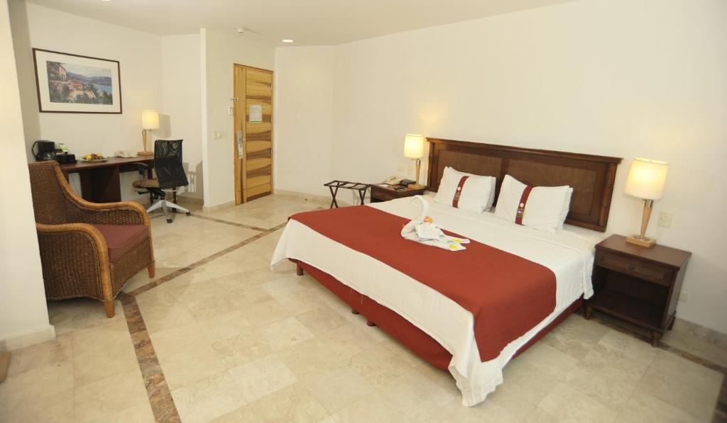 a bedroom with a large bed and a desk at Gamma Plaza Ixtapa in Ixtapa