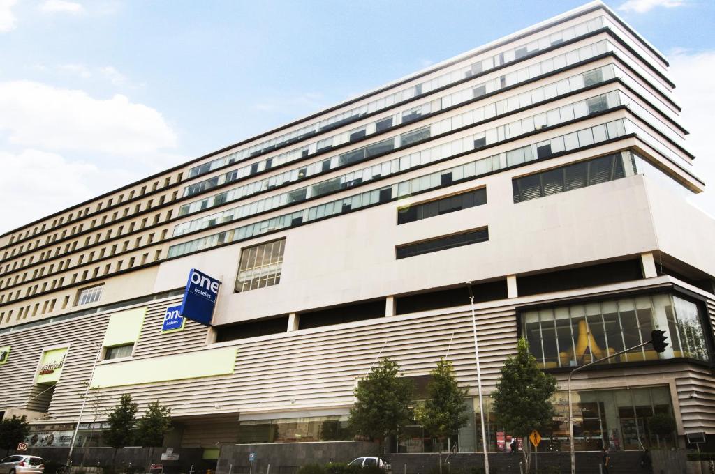 a large white building with a blue sign on it at One Ciudad de Mexico Patriotismo in Mexico City