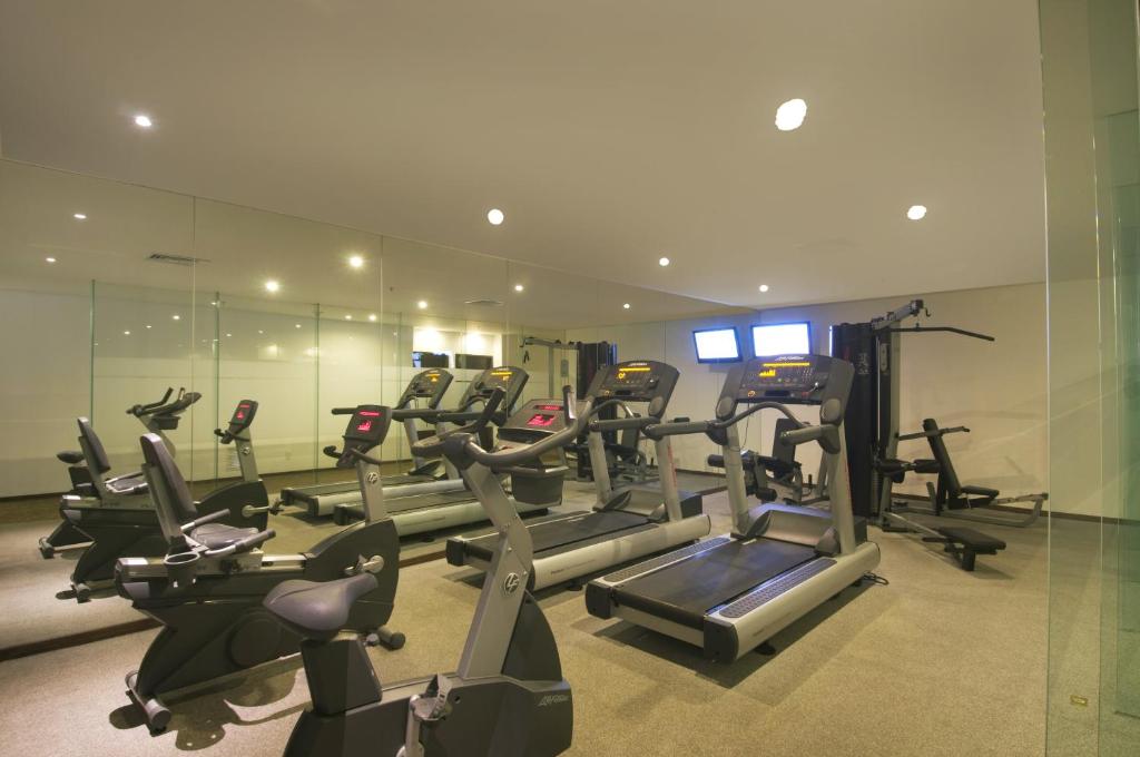 A mirrored fitness room contains cardio machines and a cable station.