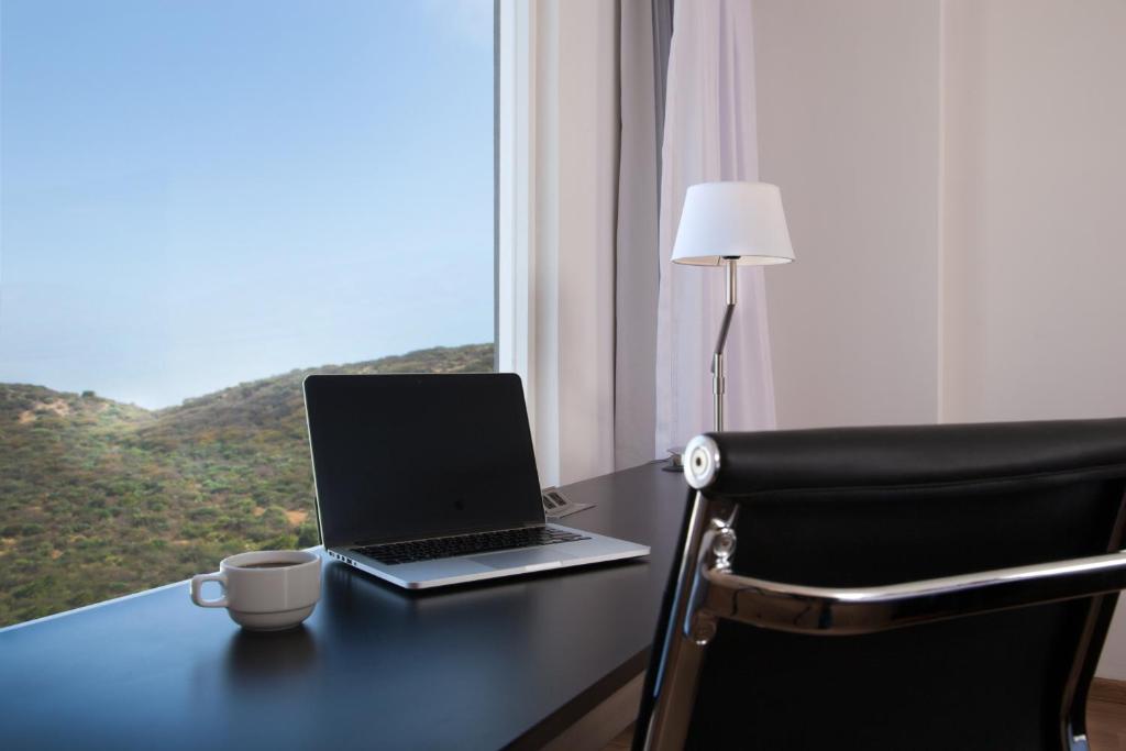 A desk beside a window with a laptop and desk chair.