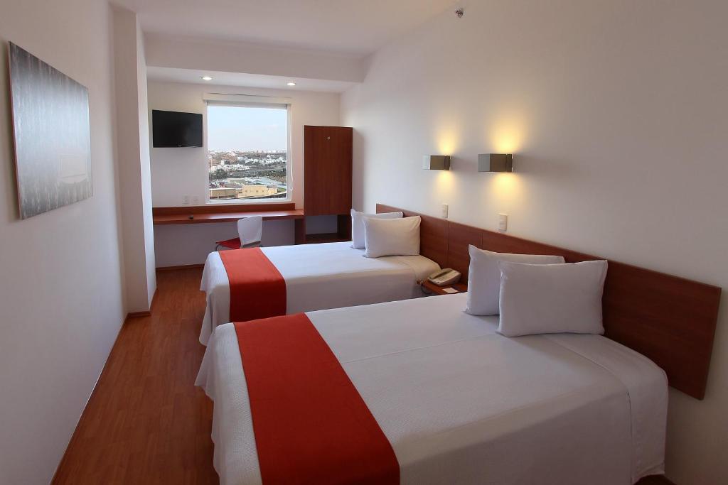 ケレタロにあるOne Queretaro Centro Surのベッド2台と窓が備わるホテルルームです。