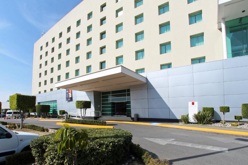 a white building with a car parked in front of it at Fiesta Inn Cuautitlan in Tepotzotlán