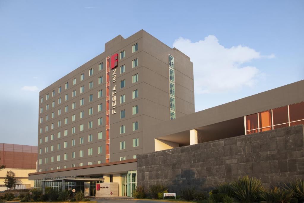 a tall building with a stone wall in front of it at Fiesta Inn Morelia Altozano in Morelia