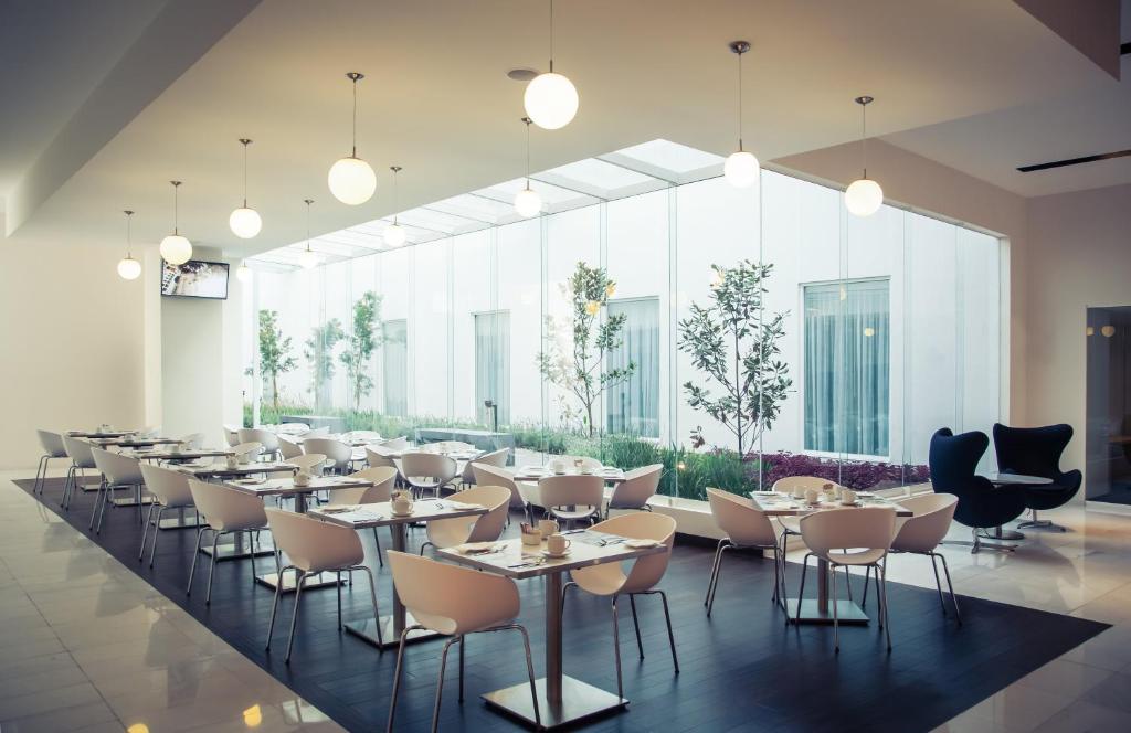 a restaurant with tables and chairs and large windows at Fiesta Inn Plaza Central Aeropuerto in Mexico City