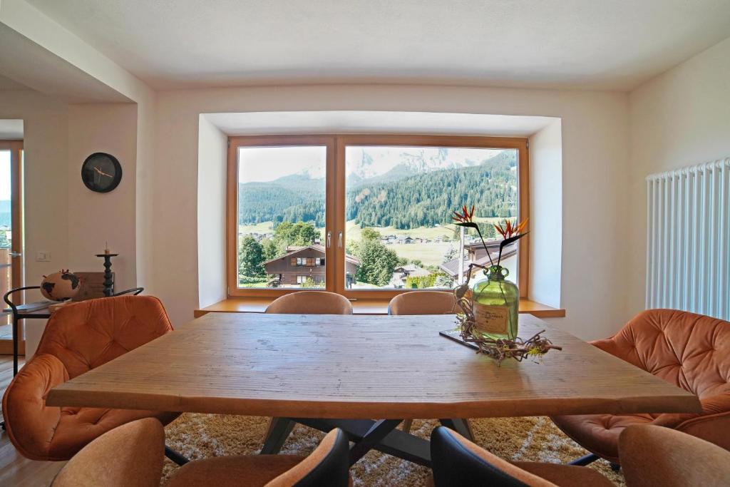 une salle à manger avec une table et une grande fenêtre dans l'établissement Design Residence Del Passo, à Padola