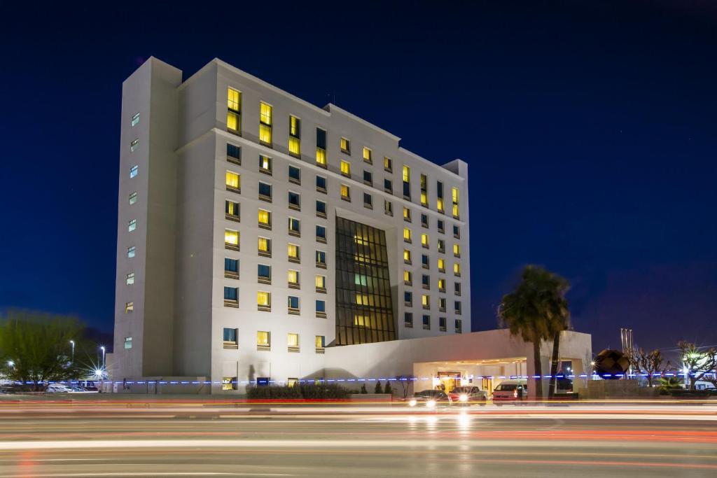 a large white building at night with a street at Fiesta Inn Ciudad Juarez in Ciudad Juárez