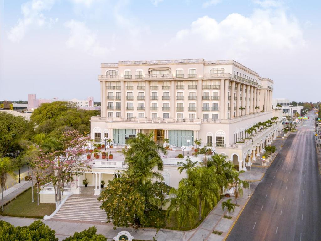 a large white building with palm trees in front of a street at Fiesta Americana Merida in Mérida