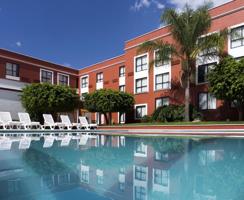 a hotel with a swimming pool in front of a building at Fiesta Inn Leon in León