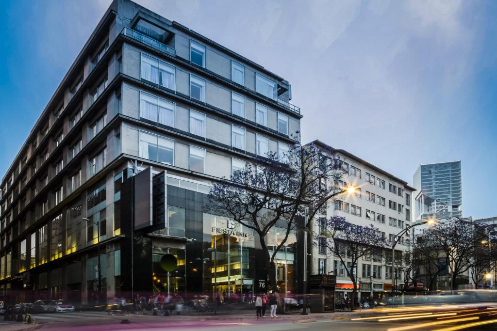 Un edificio alto in una strada cittadina con traffico di Fiesta Inn Centro Historico a Città del Messico