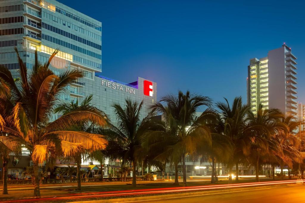 um grupo de palmeiras em frente a um edifício em Fiesta Inn Cancun Las Americas em Cancún