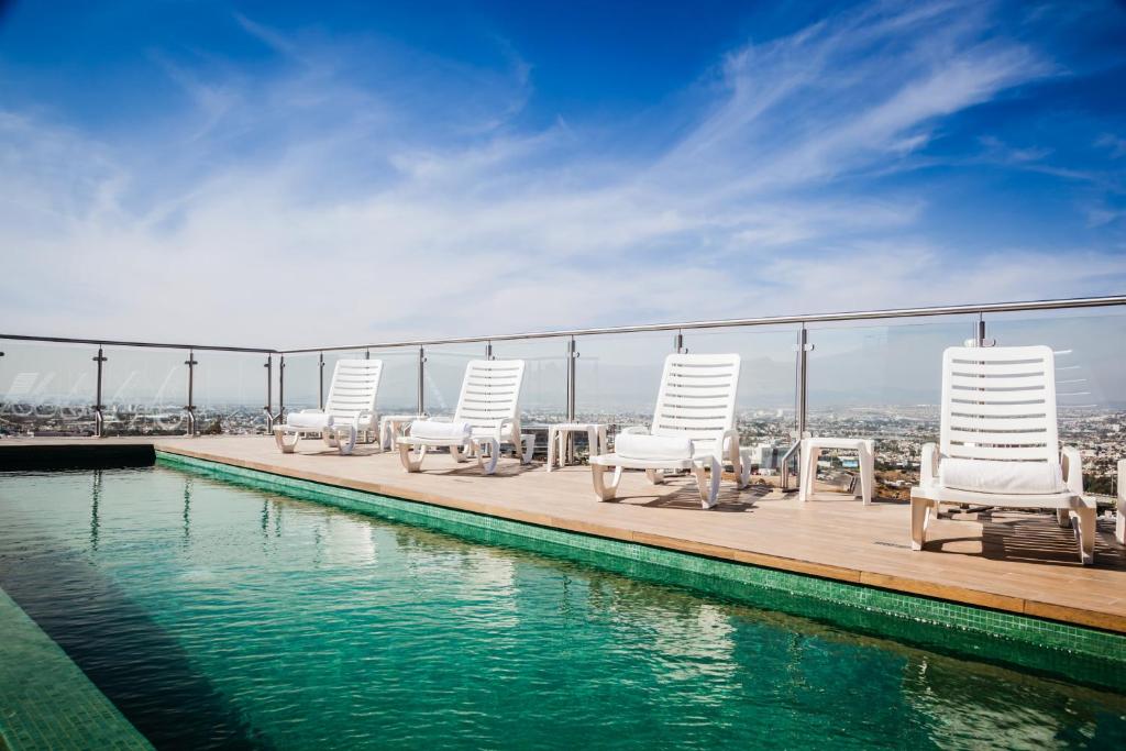 a group of chairs and tables on a deck next to the water at Fiesta Inn Queretaro Centro Sur in Querétaro