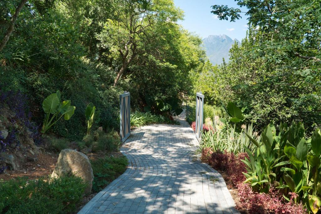 una pasarela en un jardín con árboles y plantas en Gamma Monterrey Rincon de Santiago, en Santiago