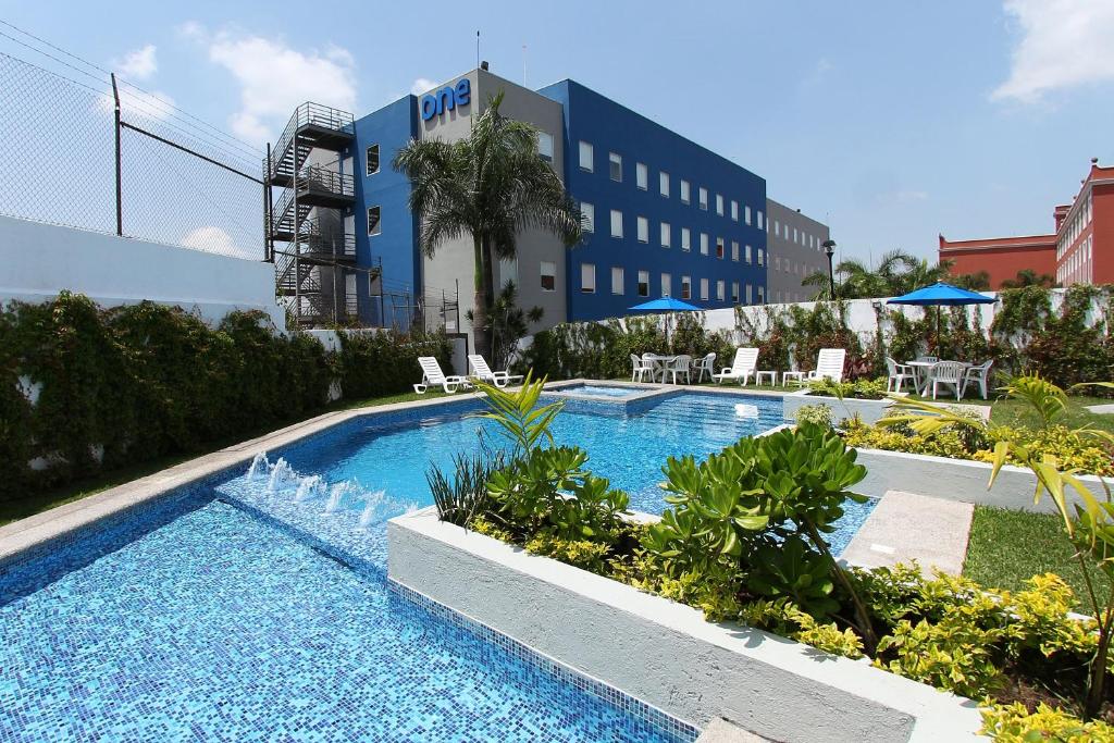 a swimming pool with a fountain in front of a building at One Cuernavaca in Cuernavaca