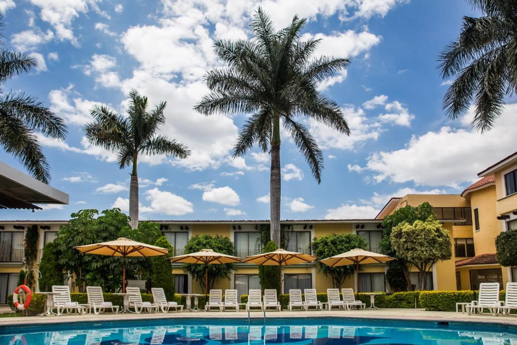 un hôtel avec une piscine et des palmiers dans l'établissement Fiesta Inn Oaxaca, à Oaxaca