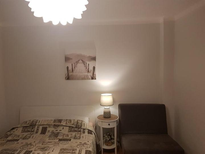 ein Schlafzimmer mit einem Bett, einer Lampe und einem Stuhl in der Unterkunft Karoso Apartment in Klaipėda