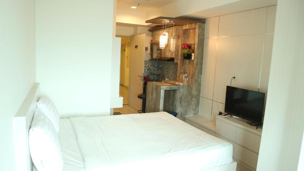 a bedroom with a white bed and a television at Apartemen Grand Kamala Lagoon by Cheapinn in Bekasi