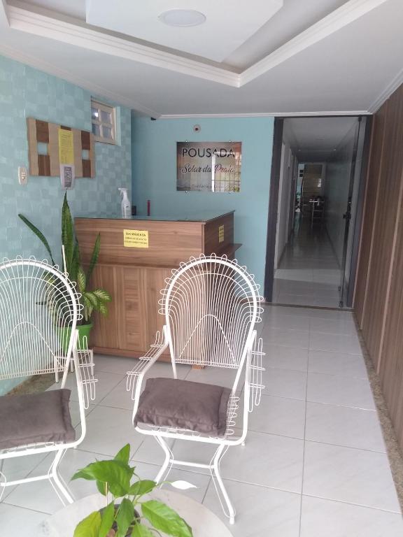 a waiting room with two white chairs and a counter at Pousada Solar da Praia in Guarapari