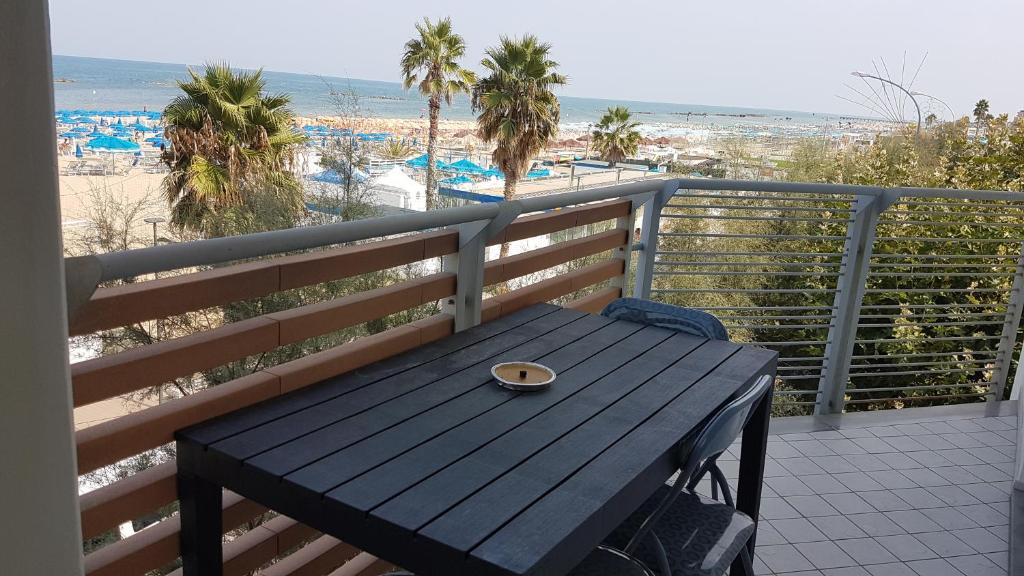 ロゼート・デッリ・アブルッツィにあるApartment Atlantic Roseto Beachの木製ベンチ(ビーチのあるバルコニーの上に座る)