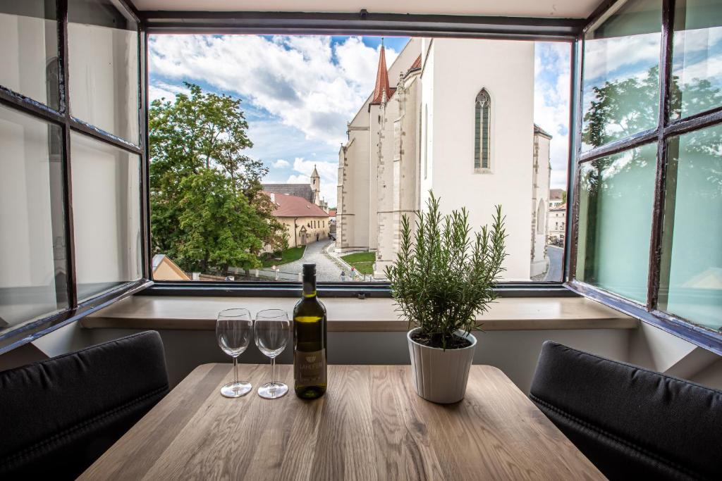 a table with a bottle of wine and two glasses at Apartmány na Mikulášském náměstí in Znojmo