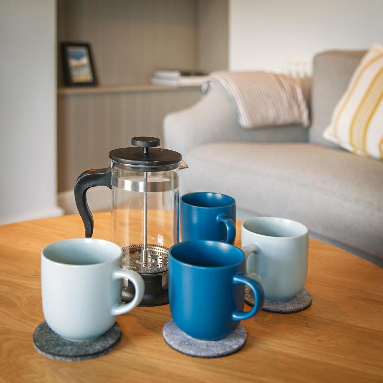 a coffee pot and four cups on a table at The Sands Sheringham in Sheringham