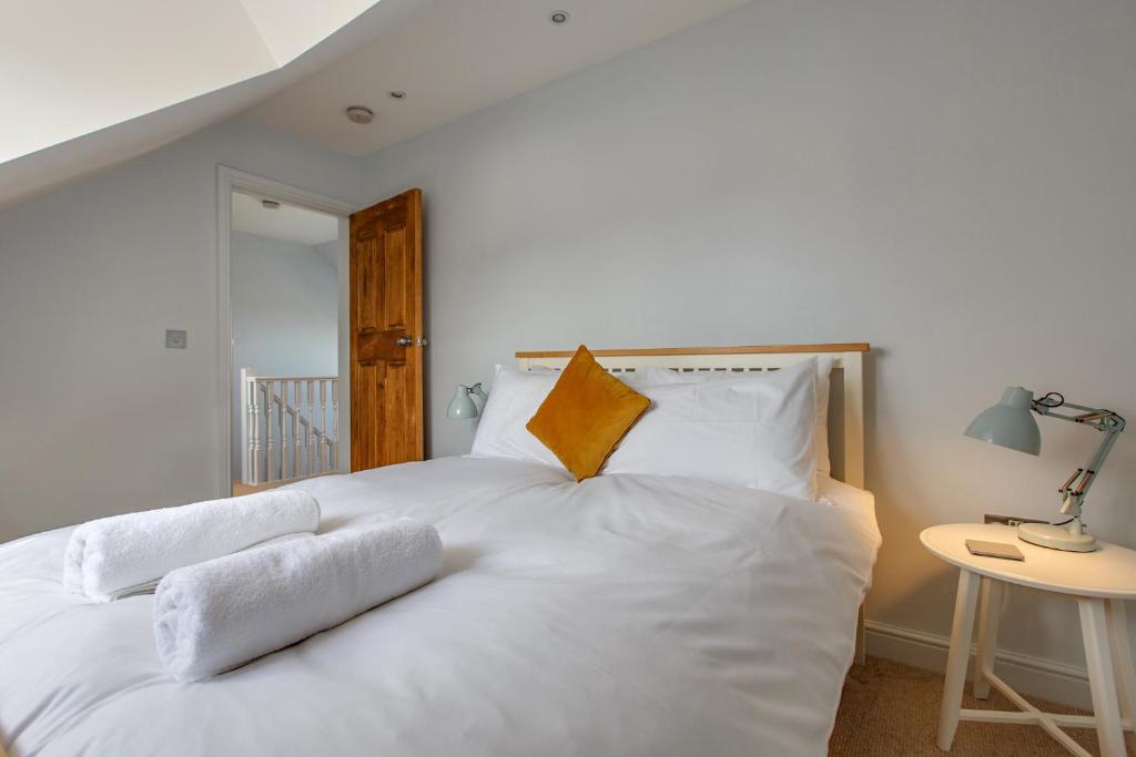a white bed with white sheets and orange pillows at The Sands Sheringham in Sheringham