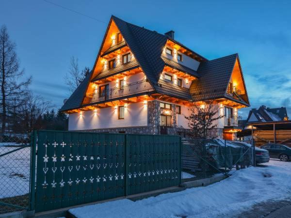 a house with a green fence in front of it at Willa Laskosia in Murzasichle