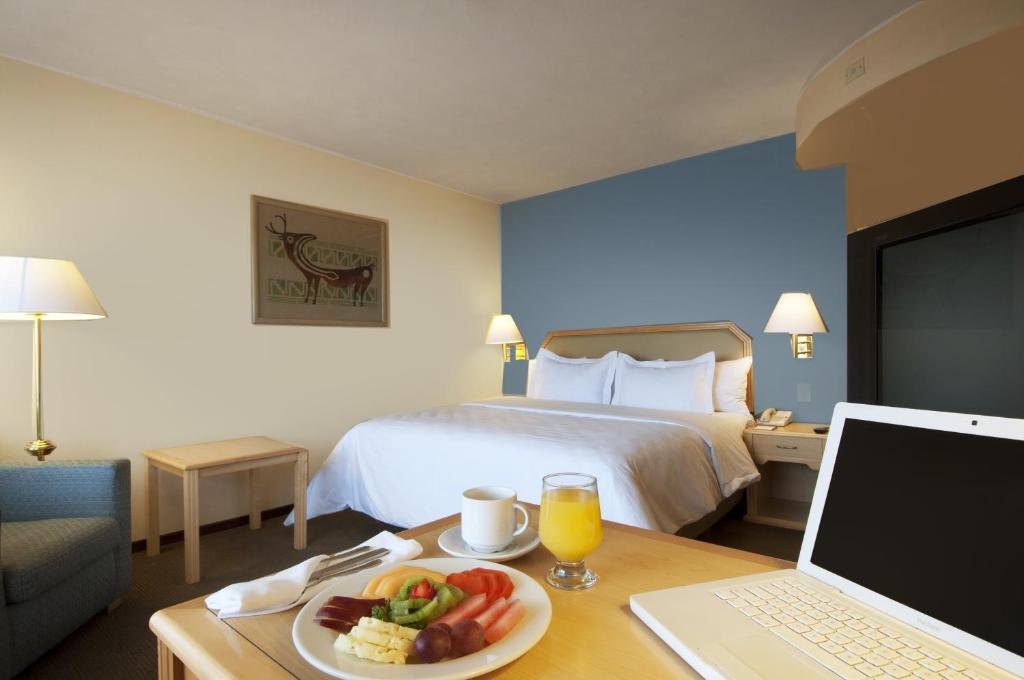 a hotel room with a bed and a table with a plate of food at Fiesta Inn Hermosillo in Hermosillo