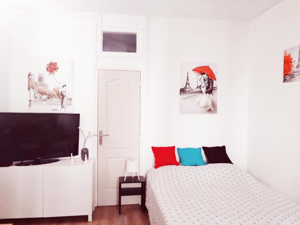 a white bedroom with a bed and a flat screen tv at Studio dans un quartier résidentiel à Montrouge avec le métro à 2 min in Montrouge