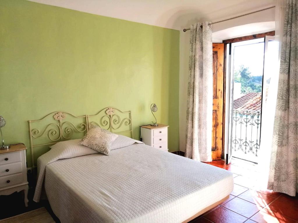 1 dormitorio con cama blanca y pared verde en Casa do Castelo II, en Arraiolos