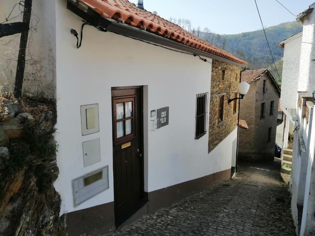 a white building with a door on a street at Casa do Alto - Benfeita in Benfeita