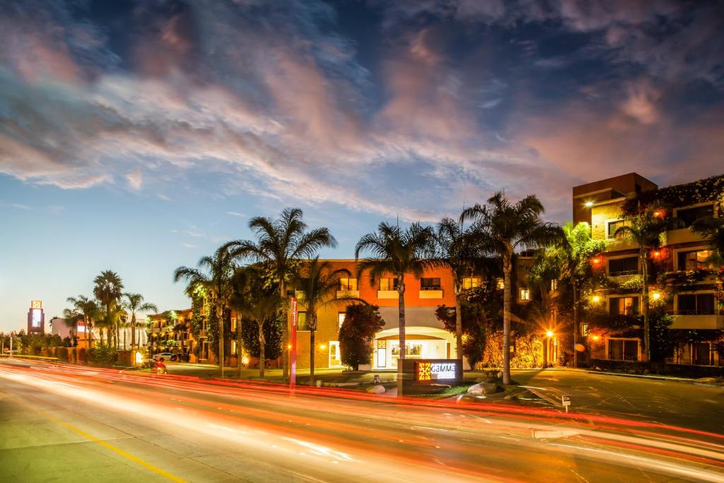 una strada cittadina con edifici e palme di notte di Gamma Tijuana a Tijuana