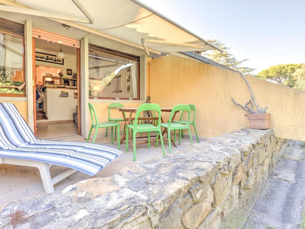un patio con sedie e tavolo su un muro di pietra di Belvilla by OYO Le Mimose nr 12 a Punta Ala