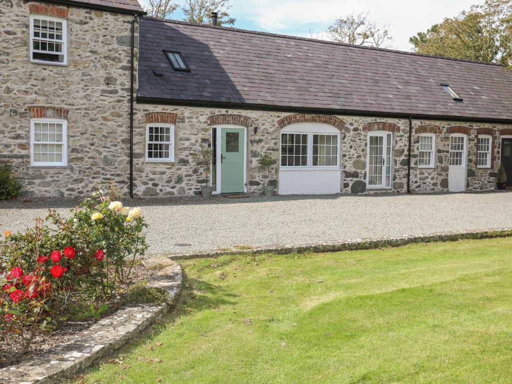 una casa de piedra con una puerta verde y un patio en The Coach House en Holyhead