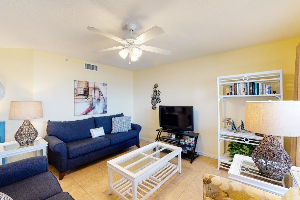 sala de estar con sofá azul y TV en Islander Condominiums III, en Fort Walton Beach