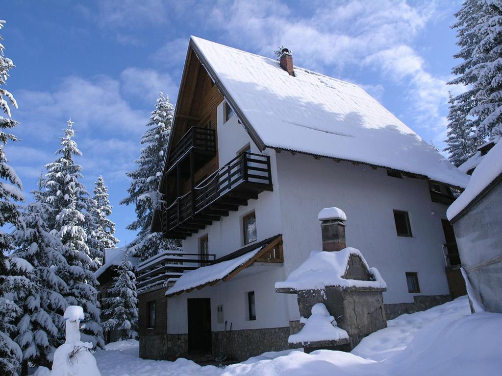 a large white house with snow on the roof at Vlašićki Konak in Vlasic