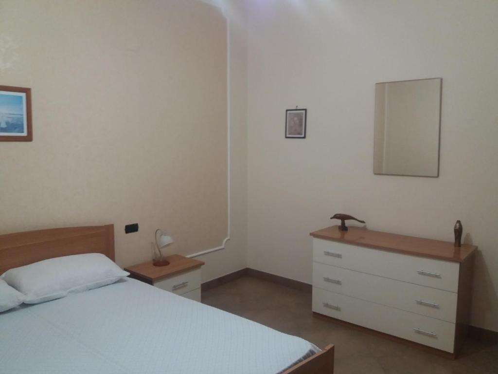 a bedroom with a bed and a dresser and a mirror at Villino Maria in Torre Faro