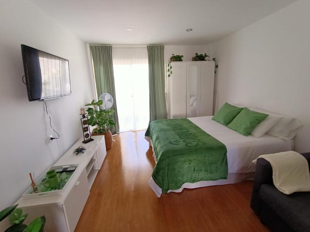 a bedroom with a bed with a green blanket on it at Apartamento vista al mar Playa Las Américas in Arona
