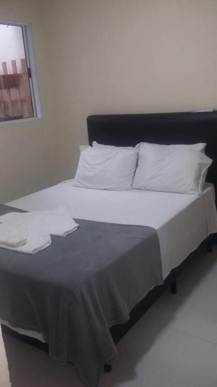 a large bed with white sheets and pillows at Loft Juquehy in São Sebastião