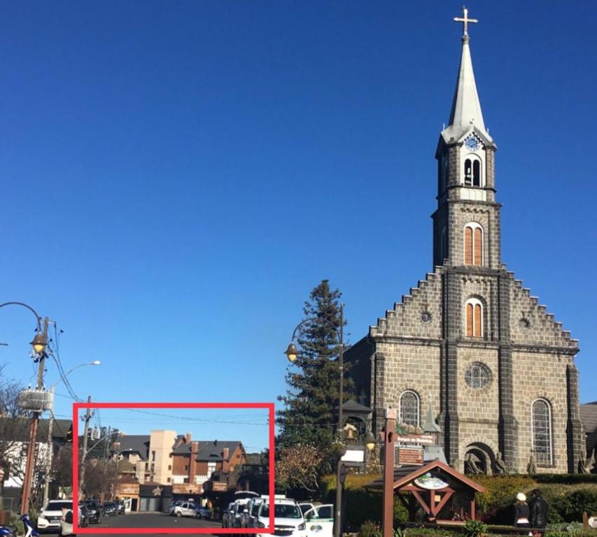 uma igreja com um campanário alto com uma moldura vermelha na frente em Centro de gramado em Gramado