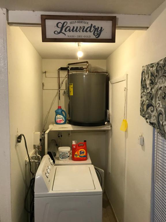 a laundry room with a washing machine and a sign on the wall at Casa Rosa All Women's Hostel in Miami