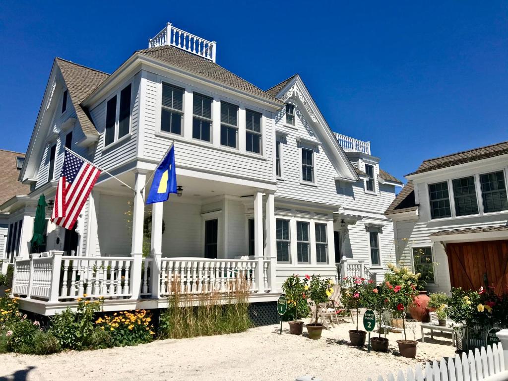 Maison blanche avec drapeau américain sur la terrasse couverte dans l'établissement White Porch Inn, à Provincetown