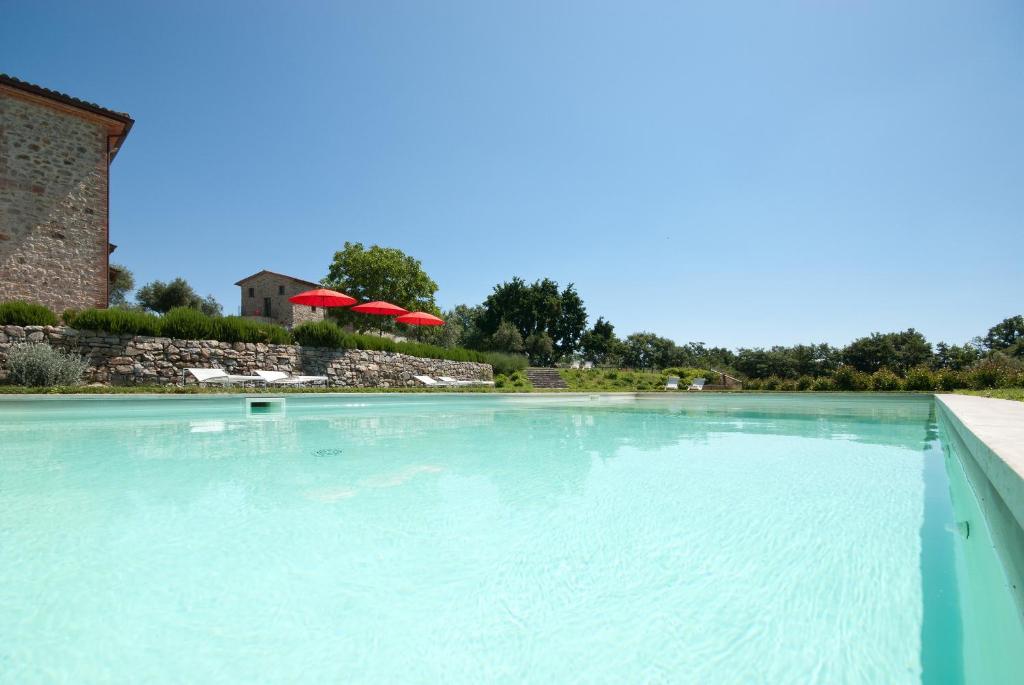 a large pool of water with two red umbrellas at Podere Le Olle B&B in Montegabbione