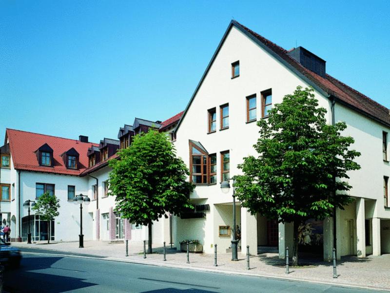 ein großes weißes Gebäude auf einer Straße mit Bäumen in der Unterkunft Hotel Lamm in Höchberg