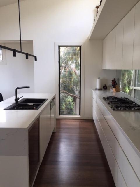 a white kitchen with a sink and a stove at Lorne Holiday House in Lorne