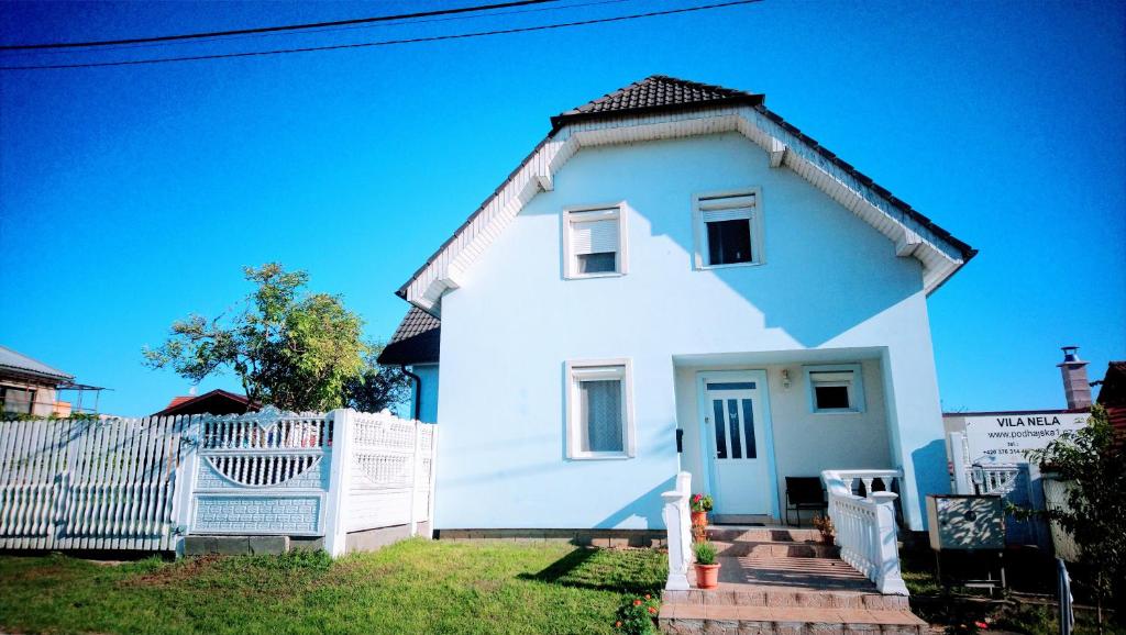 a white house with a fence in front of it at Vila Nela in Podhájska