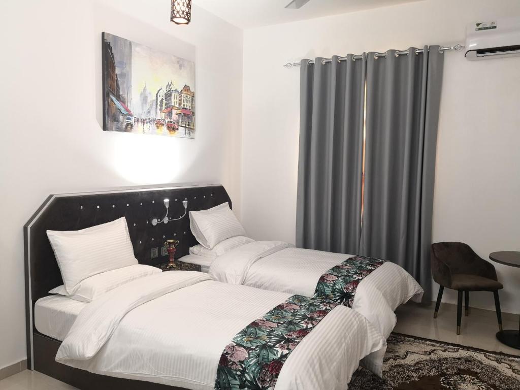 two beds in a white room with a window at Aryaf Nizwa Hotel Apartments in Nizwa