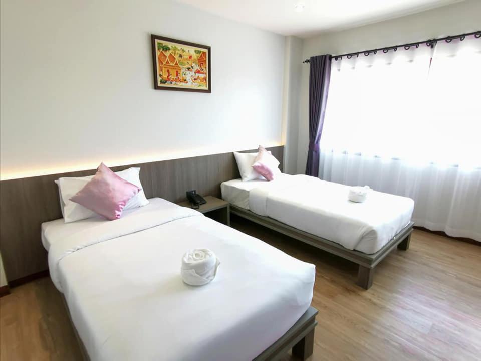 a hotel room with two beds and a window at Orchid Residence Suratthani in Surat Thani