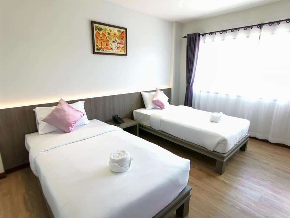 une chambre d'hôtel avec deux lits et une fenêtre dans l'établissement Orchid Residence Suratthani, à Surat Thani